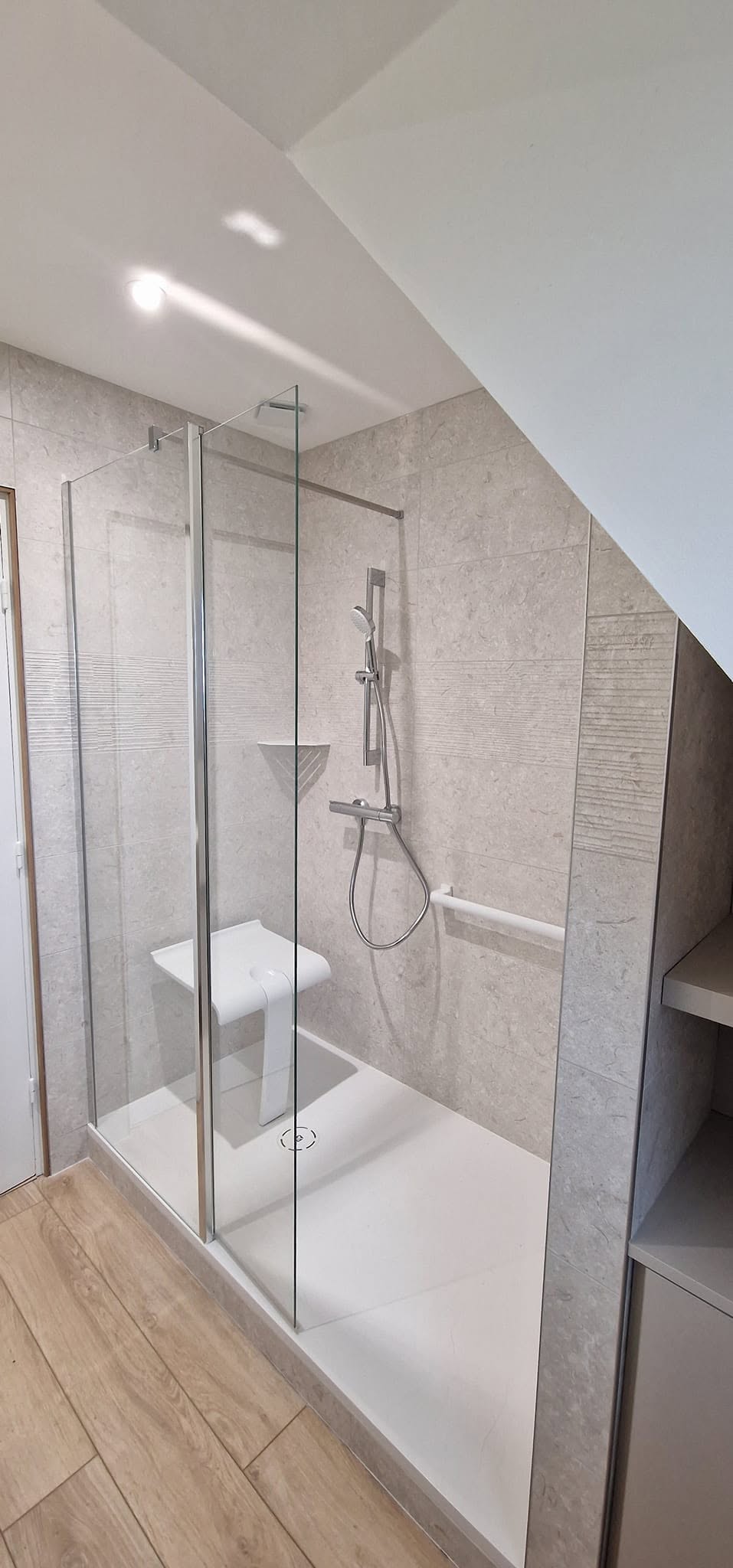 La salle de bain après travaux : douche de plain-pied avec siège et barre d'appui